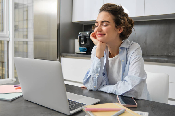 Робоча жінка використовує ноутбук вдома, робить свої податки документи, дивиться онлайн-курс на кухні. - Фото, зображення