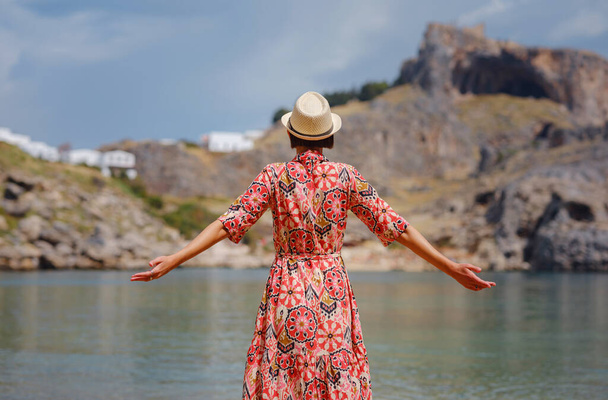 Νίκαια Ευτυχισμένη Γυναίκα Απολαμβάνοντας Ελληνικά Νησιά. Ταξίδι στην Ελλάδα, νησιά της Μεσογείου εκτός τουριστικής περιόδου. Διασκεδάζοντας με την εκπληκτική θέα στο παραθαλάσσιο θέρετρο και την παλιά πόλη της Λίνδου στο βουνό - Φωτογραφία, εικόνα