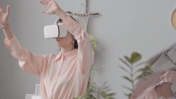 Female virtual reality developer wearing vr goggles gesticulating with her hands while testing new application in office - Footage, Video