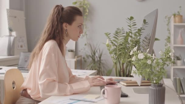 Boční pohled pomalé mladé elegantní podnikatelky pracující na stolním počítači v moderní kanceláři - Záběry, video