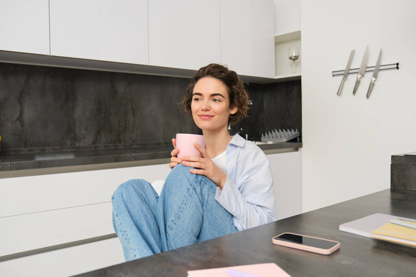 Изображение молодой взрослой женщины с чашкой кофе. Девушка отдыхает дома, пьет чай, отдыхает от работы. Человек и образ жизни - Фото, изображение