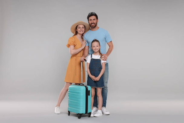 Happy family with turquoise suitcase on light grey background - Photo, Image