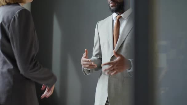 Tiro recortado de parceiros de negócios multiétnicos em formalwear tendo discussão e apertando as mãos enquanto golpeia negócio no escritório - Filmagem, Vídeo