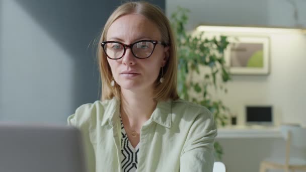 Petto fino colpo di donna d'affari bionda in occhiali da vista utilizzando il computer portatile durante la giornata lavorativa in ufficio - Filmati, video
