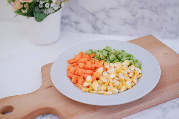 Κατεψυγμένα λαχανικά σε λευκό πιάτο σε λευκό μαρμάρινο τραπέζι. - Φωτογραφία, εικόνα