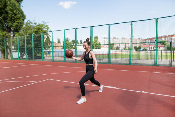 Sportovní basketbalista dribluje míč na basketbalovém hřišti. Basketbal, hry, volný čas, venkovní šablony. - Fotografie, Obrázek
