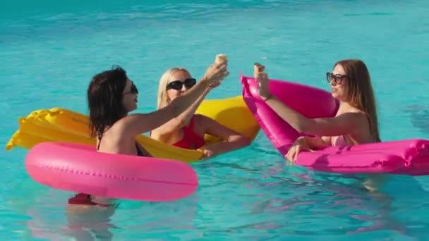 A group of beautiful young women are eating ice cream and having fun in the pool on a sunny summer day. Concept of relaxation, rest and enjoyment - Footage, Video