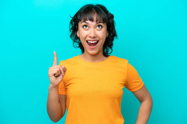 Young Argentinian woman isolated on blue background pointing up and surprised - Photo, Image