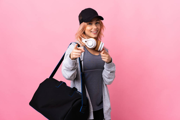 Спортивна жінка-підліток зі спортивною сумкою над ізольованим фоном здивована і спрямована спереду - Фото, зображення