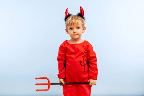 Boldog vidám fiú ördög jelmezben szigonnyal a kék háttéren. Halloween party koncepció. Web banner. - Fotó, kép