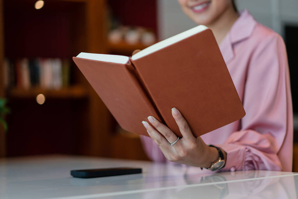 Empreendedora mulher ler livro para relaxar depois de trabalhar sobre o projeto de negócios no escritório em casa. - Foto, Imagem