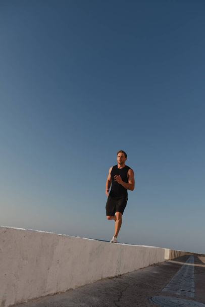 Confident young male athlete in sports clothing enjoying morning jog outdoors - Photo, Image