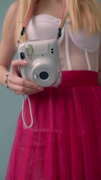 Una chica con un vestido rosa, vestida al estilo de una muñeca, toma una foto con una pequeña cámara. Imágenes de alta calidad 4k - Metraje, vídeo