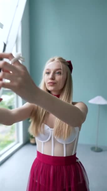 Una chica con un vestido rosa, vestida de manera inspirada en las muñecas, se toma una selfie en su teléfono inteligente. Imágenes de alta calidad 4k - Imágenes, Vídeo