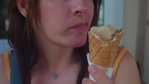 Közelkép egy nőről, ahogy jégkrémet eszik az olasz szalonban. A személy élvezi Gelato a nyári nap, cukor ínyenc desszert kezelésére - Felvétel, videó