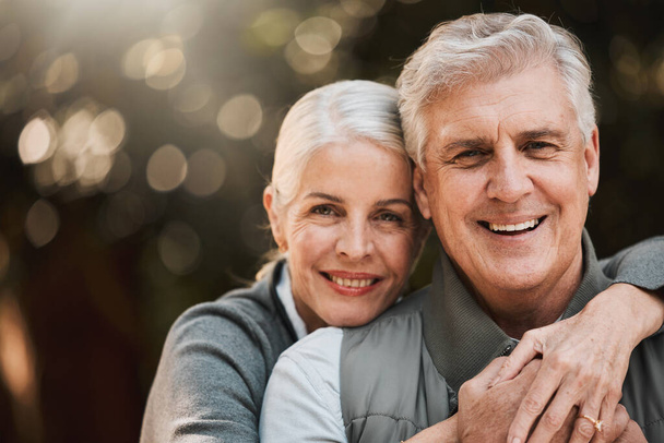 Love, portrait and senior couple hug at a park happy, free and enjoy travel, holiday or weekend. Face, smile and elderly woman embrace man in forest, bond and having fun on retirement trip together. - Photo, Image