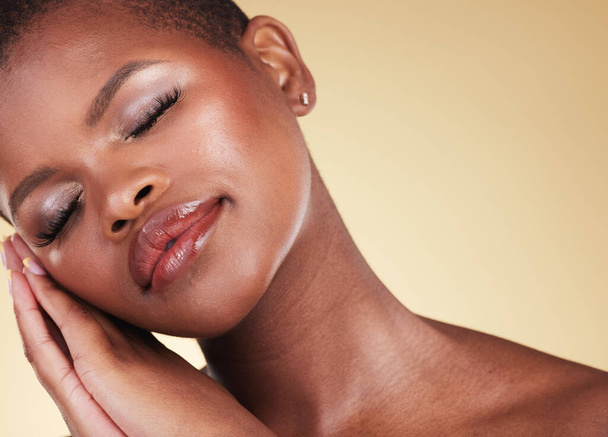Make-up, zwarte vrouw en gezicht met schoonheid in de studio voor huidverzorging, gloed en cosmetica. Headshot van een Afrikaans persoon of esthetisch model met gezichtsglans, dermatologie en wellness op een beige achtergrond. - Foto, afbeelding