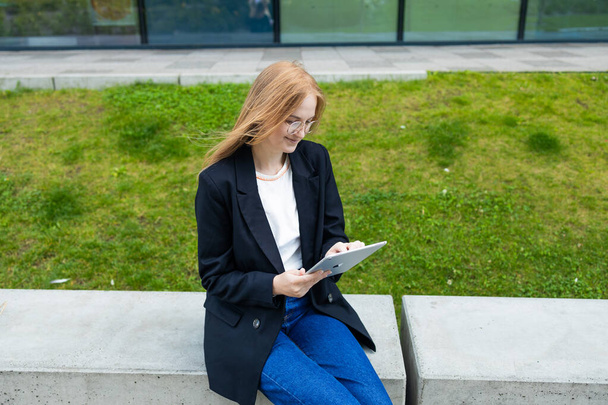 Portrait of smiling young pretty business woman at outdoors holding a tablet with happy expression. High quality photo - Zdjęcie, obraz