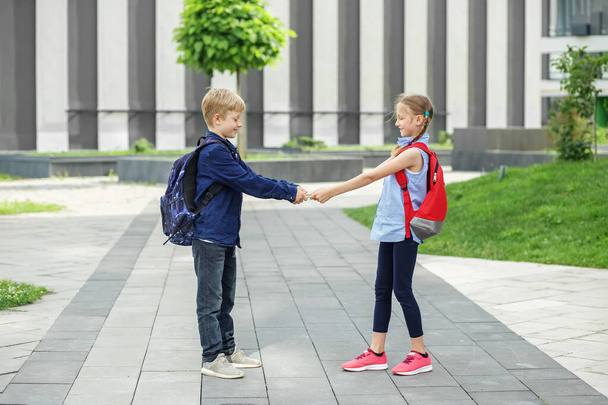 Twee kinderen met rugzakken ontmoetten elkaar op school. Terug naar school. Vrienden ontmoeten. Begin van de schoollessen. Herbruikbare waterfles - Foto, afbeelding