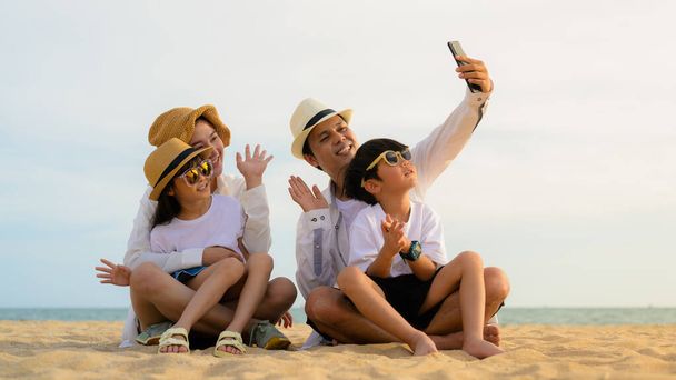 Mutlu bir aile babası, anne kız ve oğlu birlikte kumsalda zaman geçiriyorlar, plajda seyahat eden bir aile, tatilde sahilde birlikte seyahat eden mutlu bir Asyalı aile, plajda seyahat eden bir aile. - Fotoğraf, Görsel