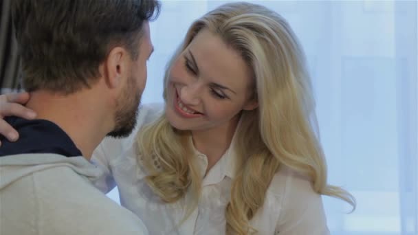 Attractive caucasian woman hugging her husband at home. Pretty blond woman holding her hand on the mans neck. Beautiful young woman stroking mans neck by her hand - Footage, Video
