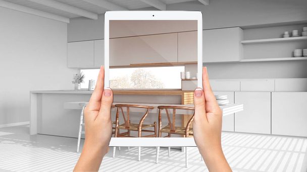 Kädet tilalla tabletti osoittaa moderni valkoinen keittiö, yhteensä tyhjä projektin tausta, täydennetty todellisuus käsite, sovellus simuloida huonekaluja ja sisustustuotteita - Valokuva, kuva
