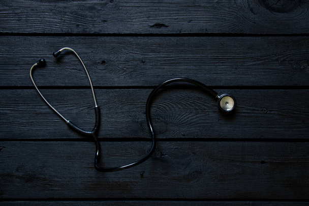 Estetoscópio encontra-se em uma tábua de madeira preta close-up, saúde e medicina - Foto, Imagem