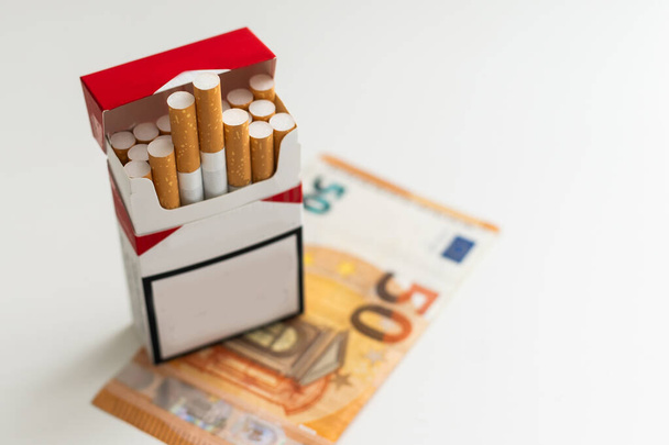 Billets de 20 et 50 euros billets comptant avec cigarettes, avec boîte à cigarettes. Concept de coût du tabac, cigarettes. Vue de face et de dessus, gros plan. Sur fond blanc. Photo de haute qualité - Photo, image