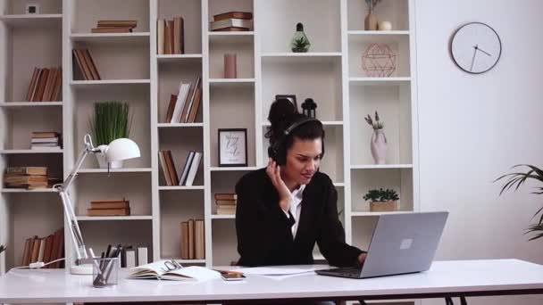 Feliz relaxado mulher de negócios latino alegre trabalhando no computador portátil no escritório usando fones de ouvido ouvindo música disco energética favorita e dança. Freelancer menina relaxante, fazendo uma pausa - Filmagem, Vídeo