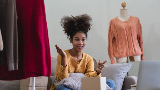 Afrykański amerykański kupiec mody kobieta prezentuje i sprzedaje ubrania online w streamingu na żywo. - Zdjęcie, obraz