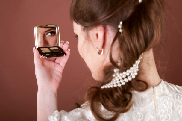 Nuori nainen katsoo pieneen peiliin
 - Valokuva, kuva