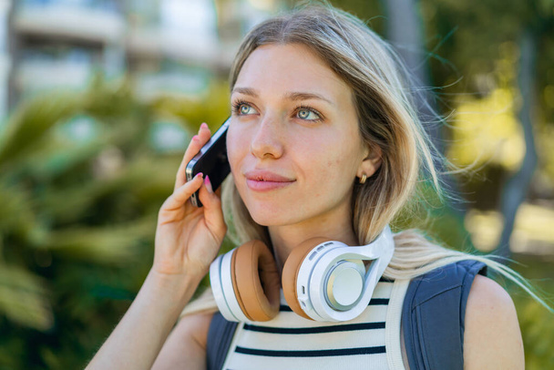 Mujer rubia joven al aire libre utilizando el teléfono móvil - Foto, Imagen