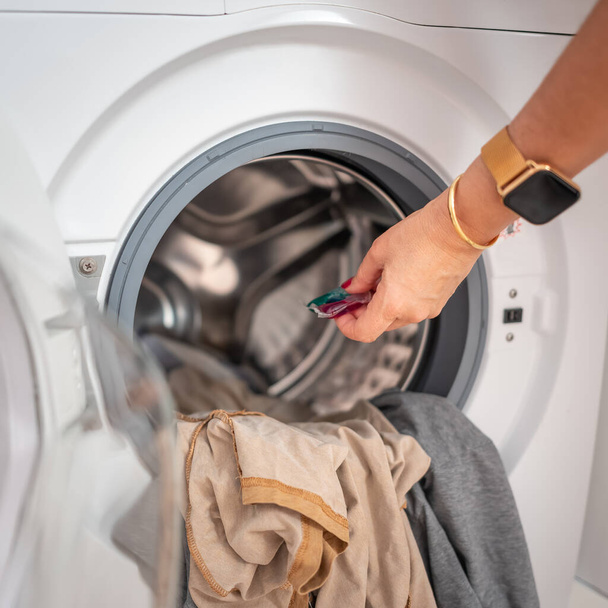 Frauen bringen Seife in biologisch abbaubaren Tabletten in die Waschmaschine, um die Wäsche zu waschen - Foto, Bild