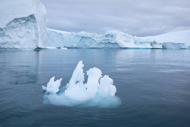Λιώνοντας ένα παγόβουνο και ρίχνοντας νερό στη θάλασσα στις ακτές της Γροιλανδίας και καταπληκτικό παγόβουνο στη θάλασσα, μπορούμε ακόμα να το δούμε αυτό πριν από την πλήρη κλιματική αλλαγή. Παγόβουνο Η υπερθέρμανση του πλανήτη. - Φωτογραφία, εικόνα