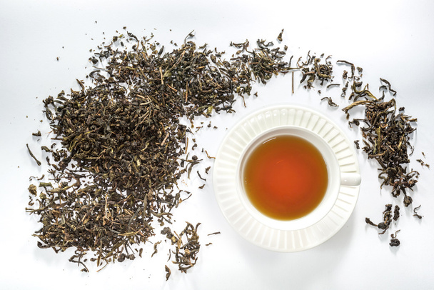 Té de taza blanca y hoja de té seca
 - Foto, imagen