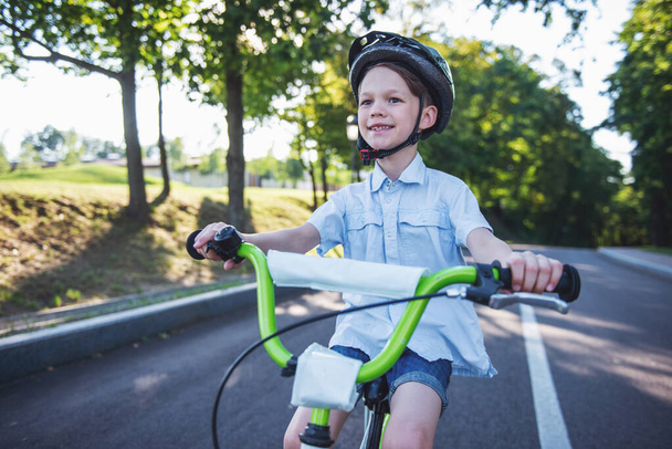 Красивий маленький хлопчик їде на велосипеді на відкритому повітрі і посміхається
 - Фото, зображення