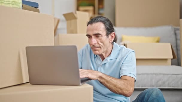 Keski-ikäinen mies käyttää kannettavaa tietokonetta istuu lattialla uudessa kodissa - Materiaali, video