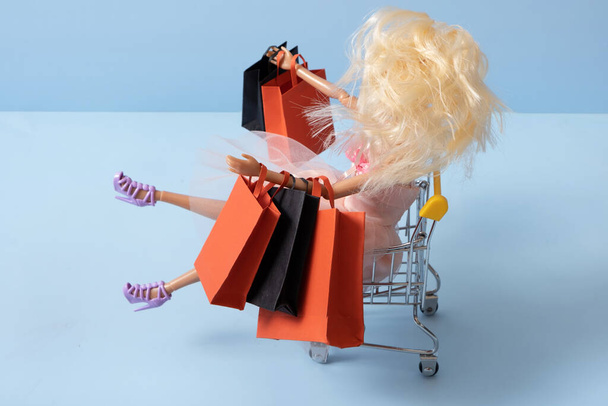 Doll in supermarket basket with shopping bag. Sale concept. - Photo, Image