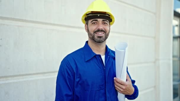 Jeune homme hispanique travailleur portant un casque dur tenant des plans à l'endroit de la construction - Séquence, vidéo