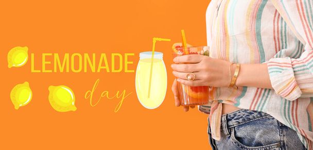 Mujer con vaso de sabrosa limonada de pomelo sobre fondo naranja - Foto, Imagen