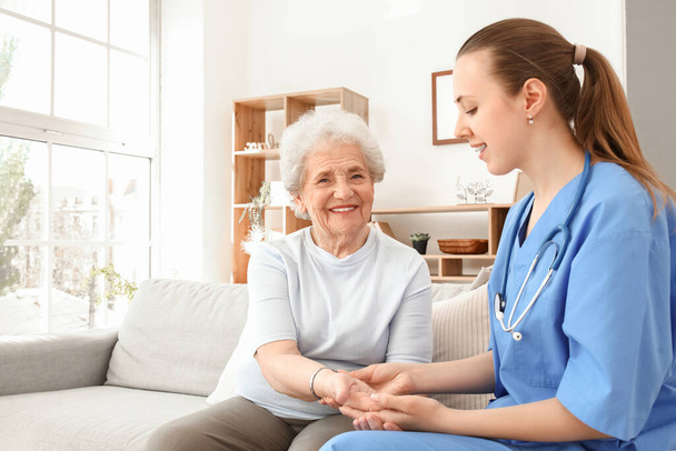 Seniorin mit Pflegerin an der Hand zu Hause - Foto, Bild