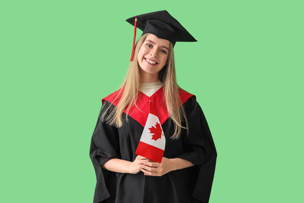 Vrouwelijke afgestudeerde student met Canadese vlag op groene achtergrond - Foto, afbeelding