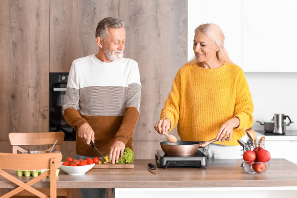 Mature couple cooking in kitchen - Photo, image