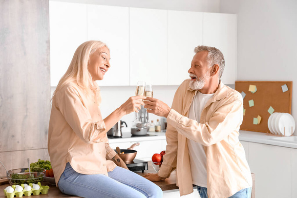 Зрелая пара пьет шампанское на кухне - Фото, изображение