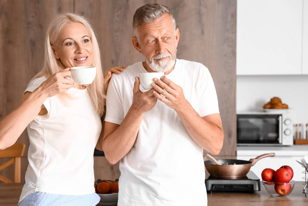 Mature couple drinking coffee in kitchen - Fotoğraf, Görsel