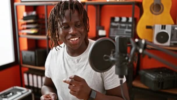 Африканский американский музыкант улыбается уверенно поющей песне в музыкальной студии - Кадры, видео