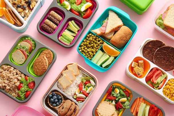 Viele Lunchboxen mit verschiedenen leckeren Speisen auf rosa Hintergrund - Foto, Bild