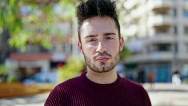 Νεαρός Ισπανός στέκεται με σοβαρή έκφραση στο πάρκο - Πλάνα, βίντεο