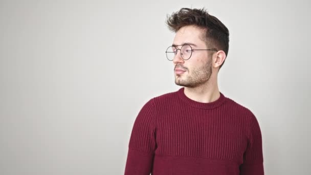 Joven hombre hispano sonriendo señalando hacia un lado sorprendido sobre un fondo blanco aislado - Metraje, vídeo
