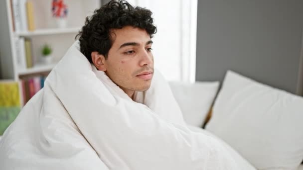 Jovem homem latino cobrindo com cobertor bocejando no quarto - Filmagem, Vídeo
